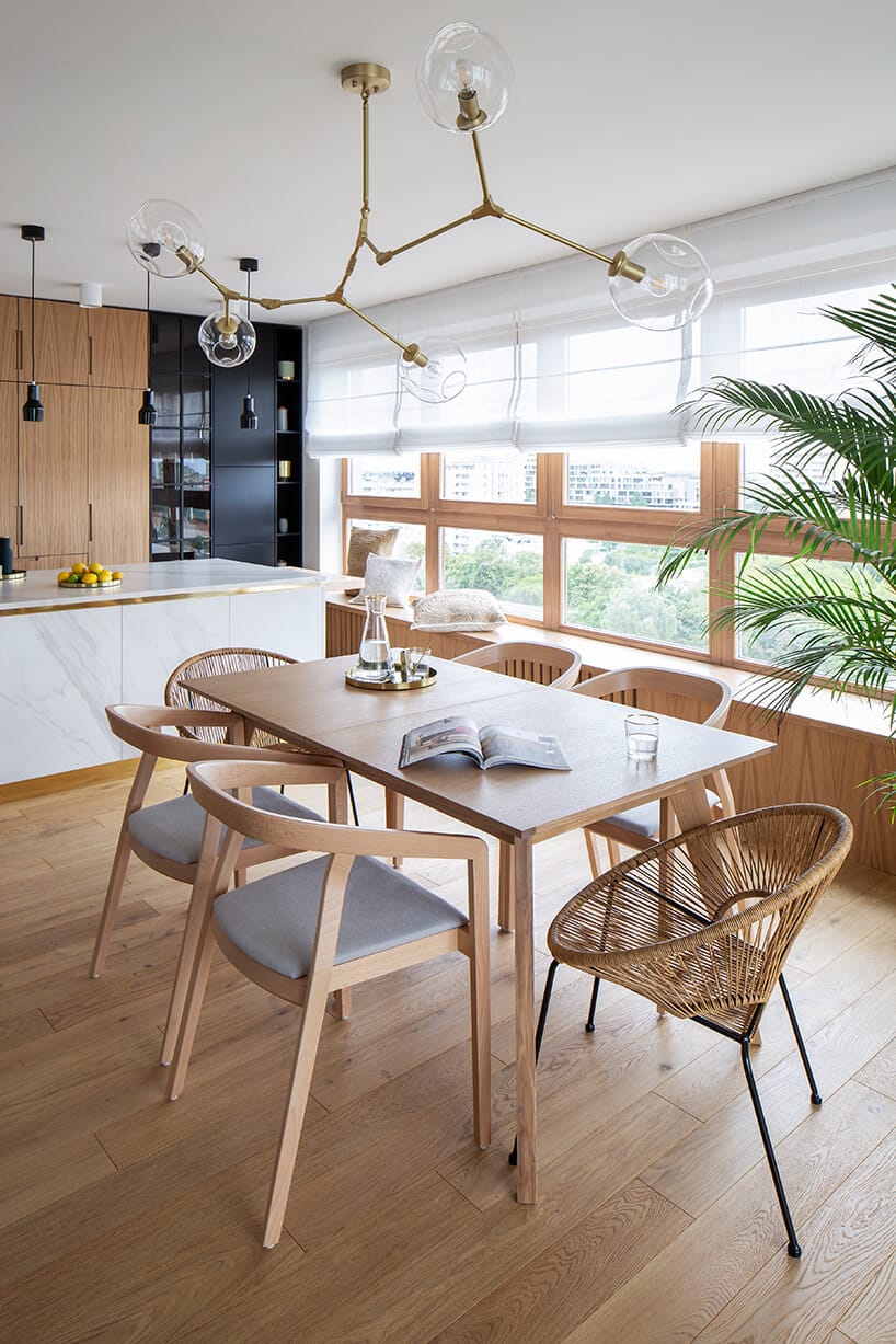 nowoczesny apartament z drewnianym stołem z sześcioma krzesłami pod wyjątkową złota lampą z przeźroczystymi szklanymi kloszami