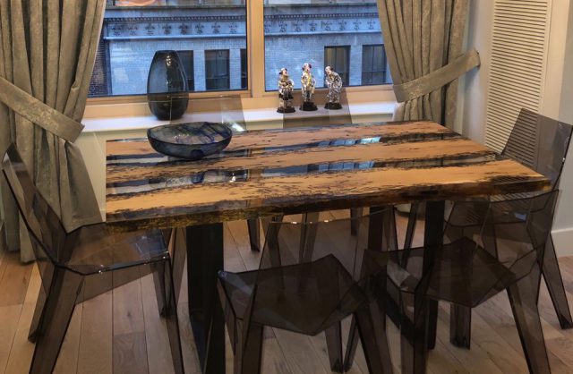 duży stół ze szklano-drewnianym blatem i przeźroczystymi ciemnymi krzesłami