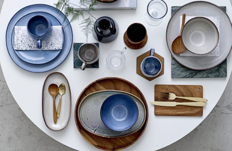 biały stół z niebieskim talerzami oraz dodatkami drewnianymi