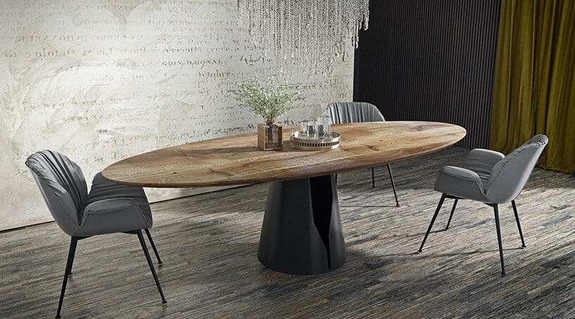 owalny drewniany stół na zawężanej tulei na jasnych deskach