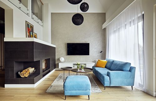 nowoczesne wnętrze salonu z narożnym ciemnym kominkiem i niebieską sofą