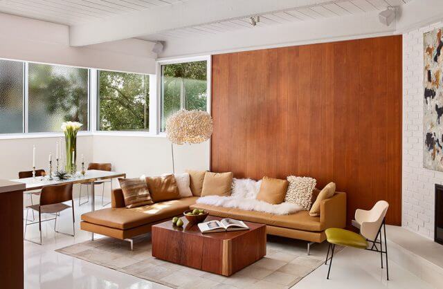 salon z narożną sofą na tle drewnianej ściany