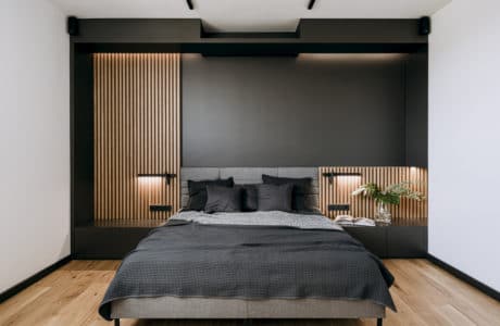 nowoczesna sypialnia z kawałkiem czarnej ściany i szarym łóżkiem