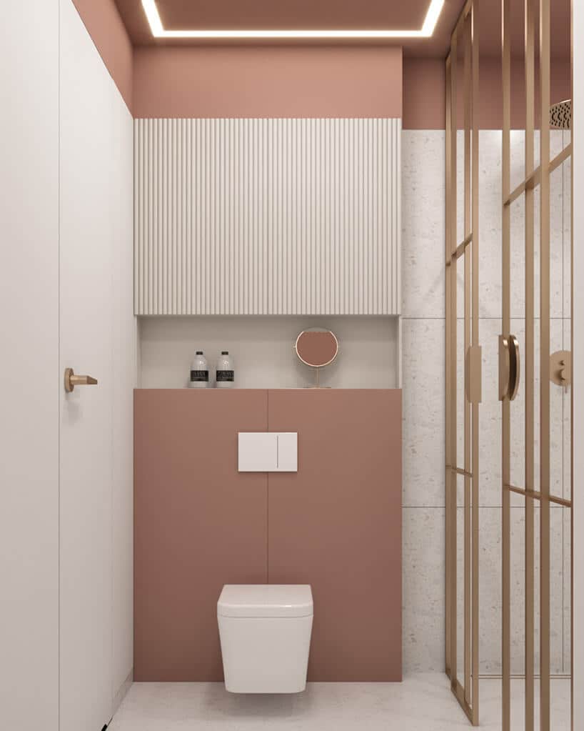 biała wisząca toaleta na lekko różowej ścianie obok białych drzwi ze złotą klamką