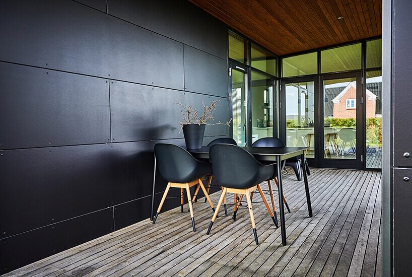 wnętrze jadalni z czarnym stołem i krzesłami oraz przy ścianie wyłożonej metalowymi czarnymi panelami