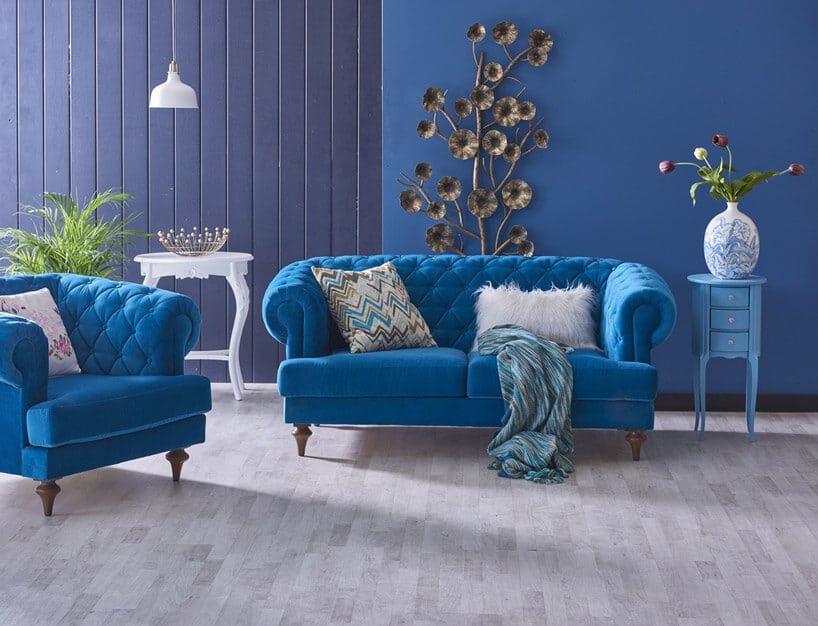 niebieskie kanapy białe poduszki niebiesko fioletowe ściany szara podłoga