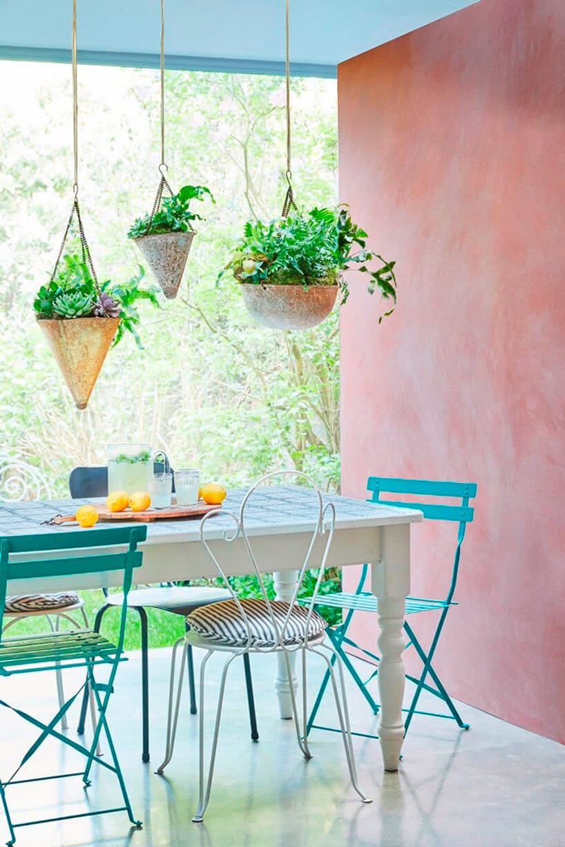 różowa ściana niebieskie krzesła niebiesko biały stół rośliny w tle