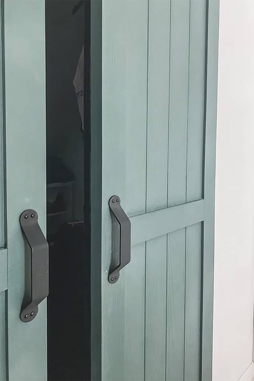 jasno niebiesko-zielone drzwi ze stodoły przy białej ścianie