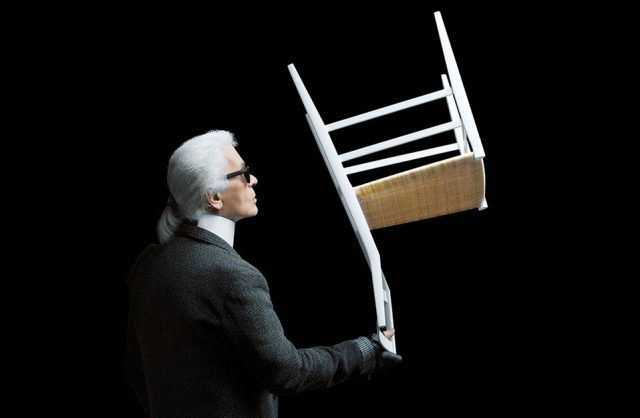 Karl Lagenferd trzymający odwrócone białe krzesło