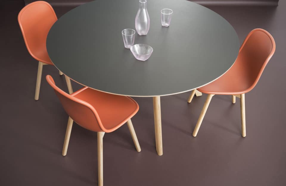szary drewniany okrągły stół z trzema drewnianymi krzesłami z pomarańczowym siedziskiem