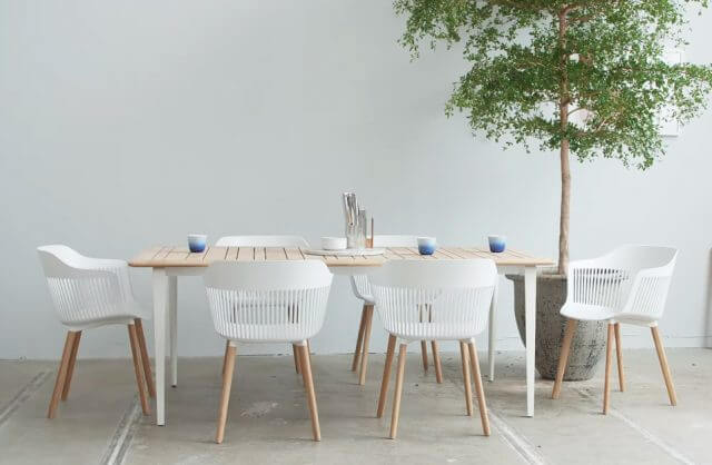 sześć białych krzeseł FRESH AIIR przy prostym drewnianym stole obok drzewka w doniczce