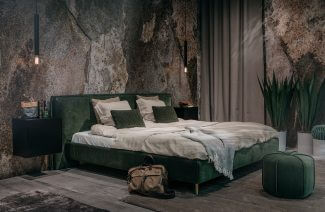 duże zielone łóżko na tle ścian z kamienia