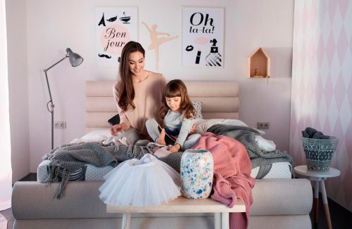 dziewczynka z mamą siedzą na materacu kieszeniowym w sypialni w pastelowych kolorach
