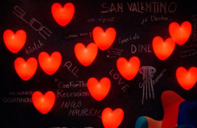 czarna ściana z napisami kredowymi i czerwonymi świecącymi sercami