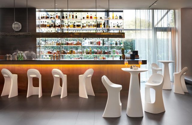bar z białymi wysokimi plastikowymi stołkami i stolikiem