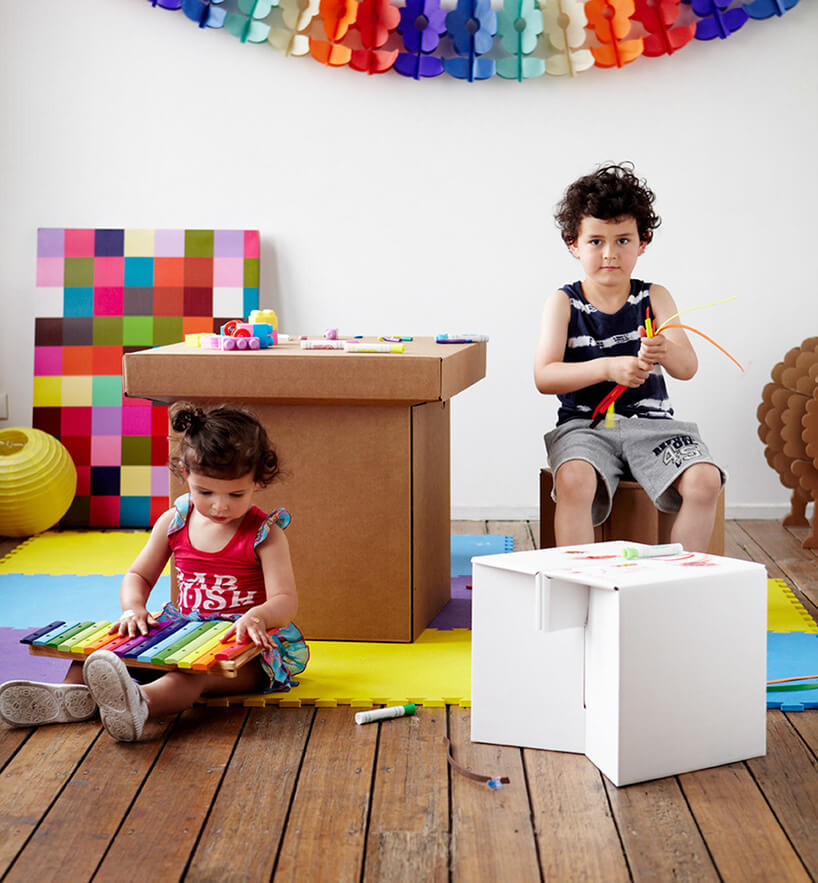 dzieci w kolorowym pokoju z tekturowymi meblami