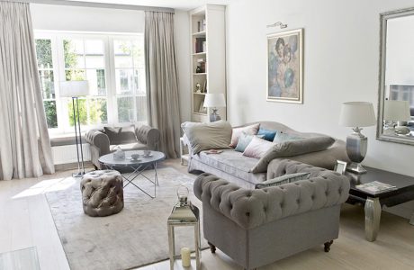 eleganckie wnętrze projektu MIśkiewicz Design salon szara sofa z dwoma szarymi fotelami i błyszcząca pufą