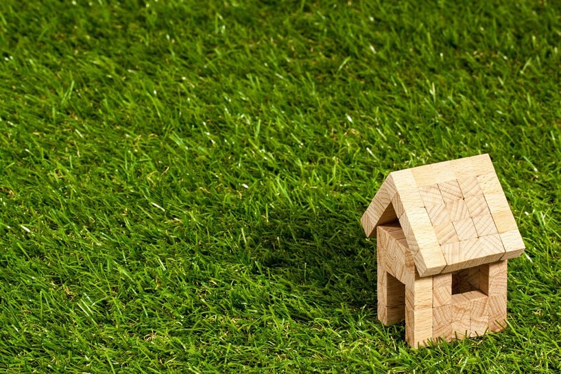 mały domek zabawka z drewnianych klocków na zielonej trawie