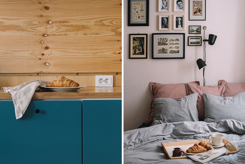drewniana szafka kuchenna z niebieskim frontami na tle ściany wykończonej drewnem obok łóżka stojącego pod ścianą z wieloma ramkami