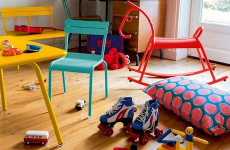 kolorowy stolik, krzesła, ławeczka dla dzieci i koń na biegunach w pokoju dziecięcym