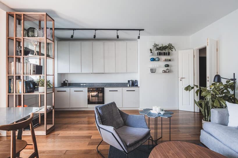 minimalistyczne wnętrze od Taff Architekci biały aneks kuchenny połaczony z salonem ciemną drewnianą podłogą