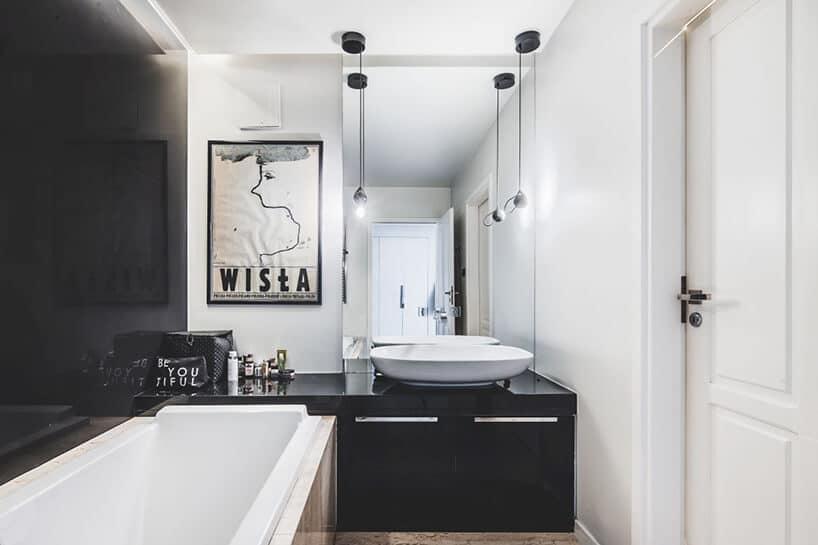 minimalistyczne wnętrze od Taff Architekci biąła łazienka z czarnymi szafkami dużym lustrem i umywalką wolonostojącą