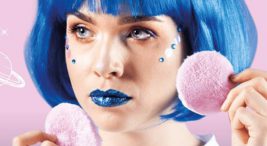 kobieta o niebieskich włosach i ustach trzyma dwa różowe pady do nakładania makijażu