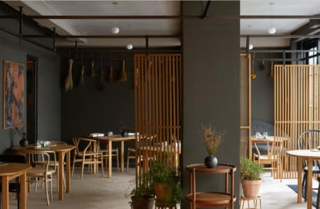 wnętrze restauracji w kolorze szarym z dodatkami jasnych drewnianych stolików