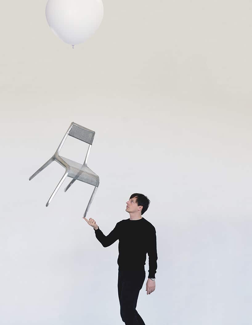 srebrne bardzo lekkie krzesło Ultraleggera trzyma na jednym palcu przez projektanta Oskara Zięte