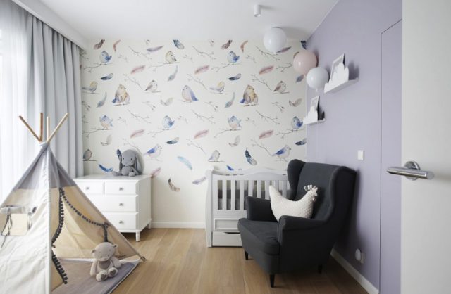 pokój dla dziewczynki z jedną lekko fioletową ścianą obok białej ściany z tapetą z rysowanymi ptakami