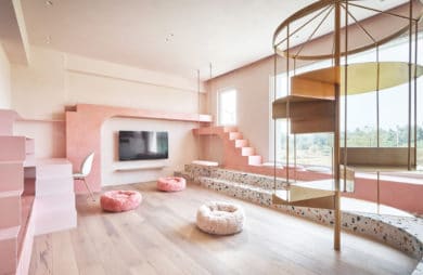 różowe wnętrze salonu ze złotymi kręconymi schodami