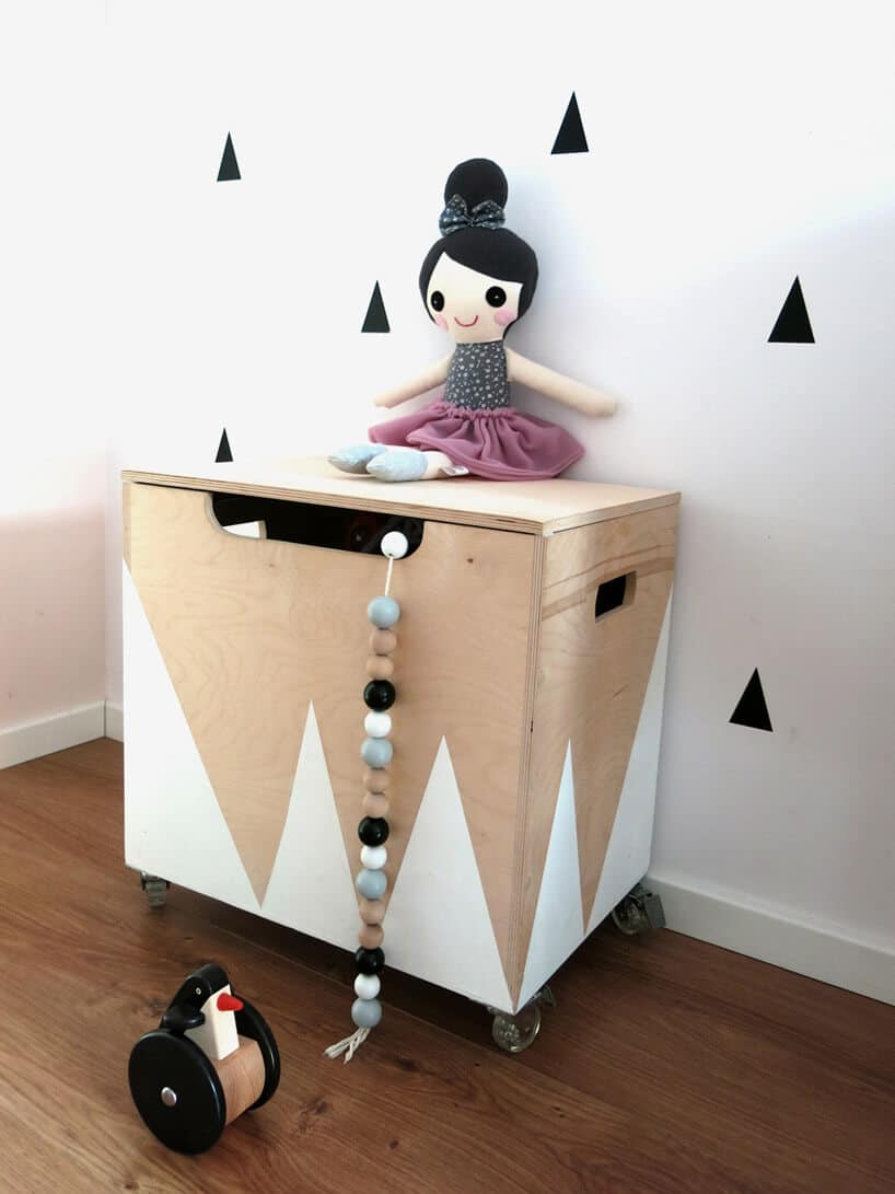 szafka z białymi trójkątami a na niej szmaciana lalka