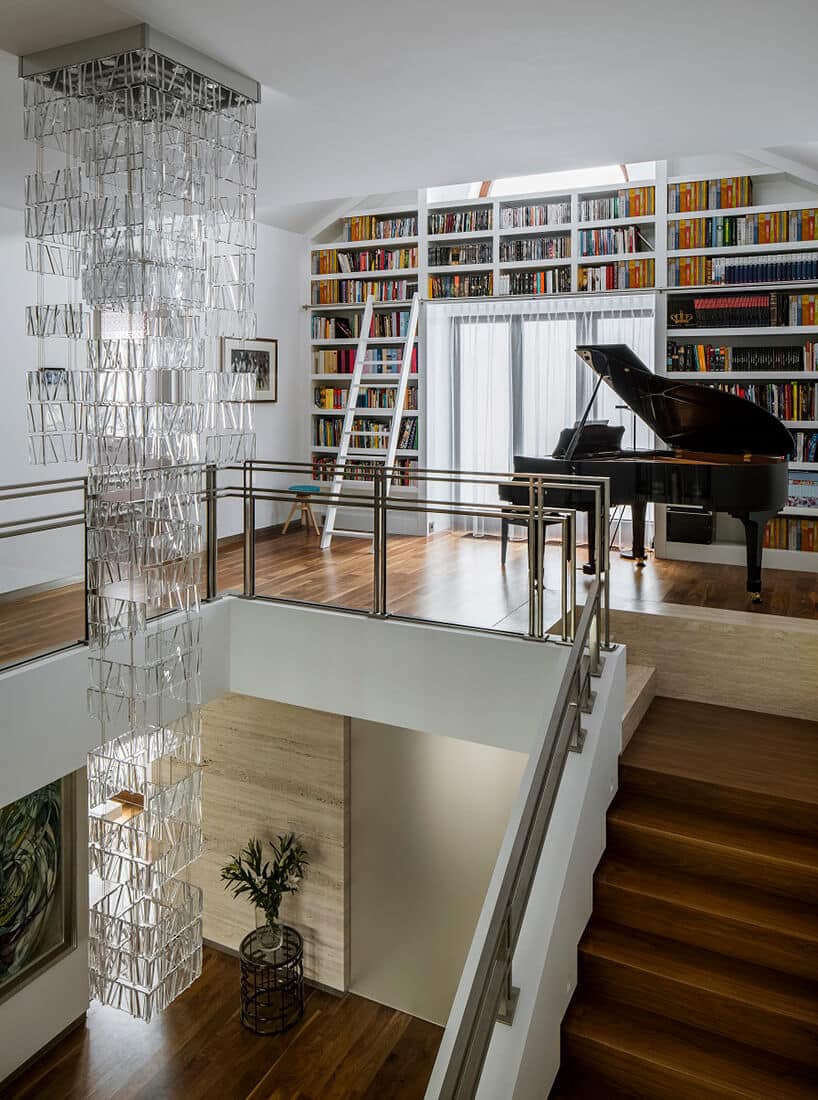 piętro w eleganckim domu z fortepianem na tle biblioteczki z białą drabiną wokół okna