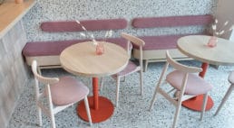 lodziarnia z różowymi obiciami krzeseł oraz siedzisk przy ceglanych ścianach oraz zaokrąglanych lustrach