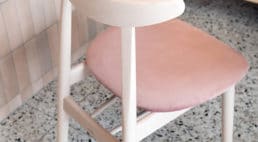 lodziarnia z różowymi obiciami krzeseł oraz siedzisk przy ceglanych ścianach oraz zaokrąglanych lustrach