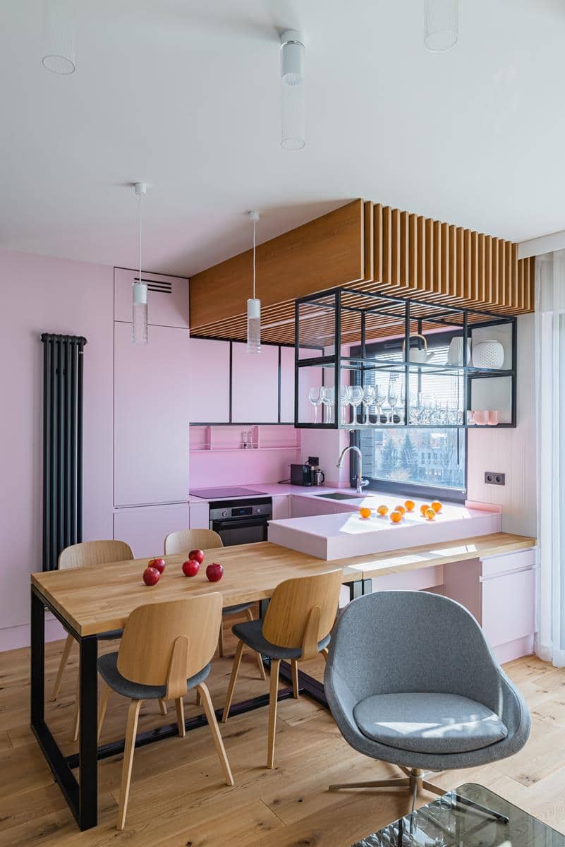 wnętrze z zdrewnianym stołem i różowa ścianą w kuchni