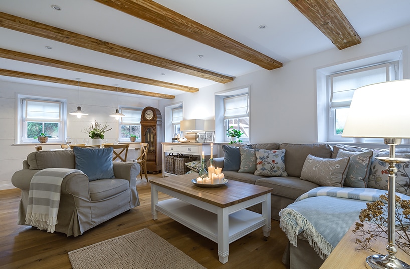 eleganckie klasyczne białe wnętrze salonu z drewnianą podłogą z szarym fotelem i sofą