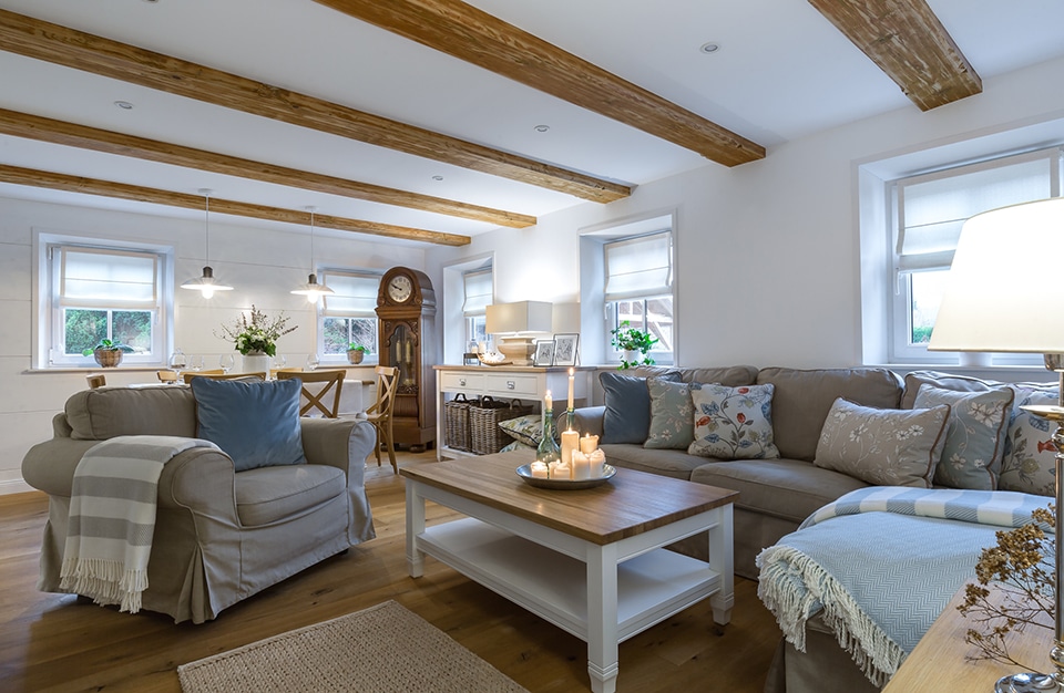 eleganckie klasyczne białe wnętrze salonu z drewnianą podłogą z szarym fotelem i sofą