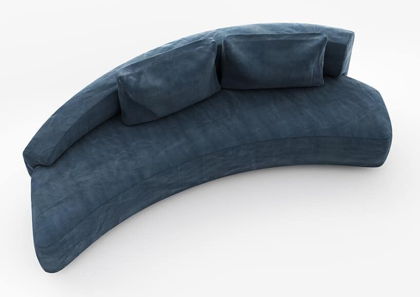 ciemno niebieska kanapa w kształcie lekkiego bumeranga z poduszkami