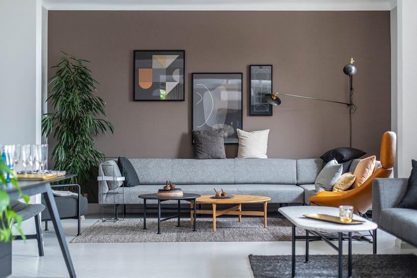szara nowoczesna niska sofa na tle jasno brązowej ściany