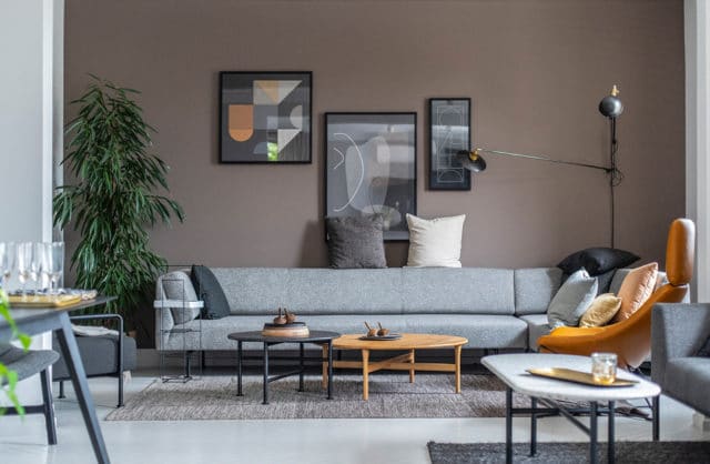 szara nowoczesna niska sofa na tle jasno brązowej ściany