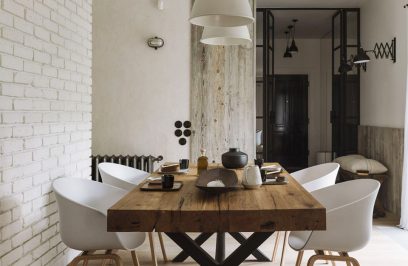 jasne wnętrze jadalni z dużym stołem z drewnianym grubym blatem z białymi plastikowymi fotelami na drewnianych nogach