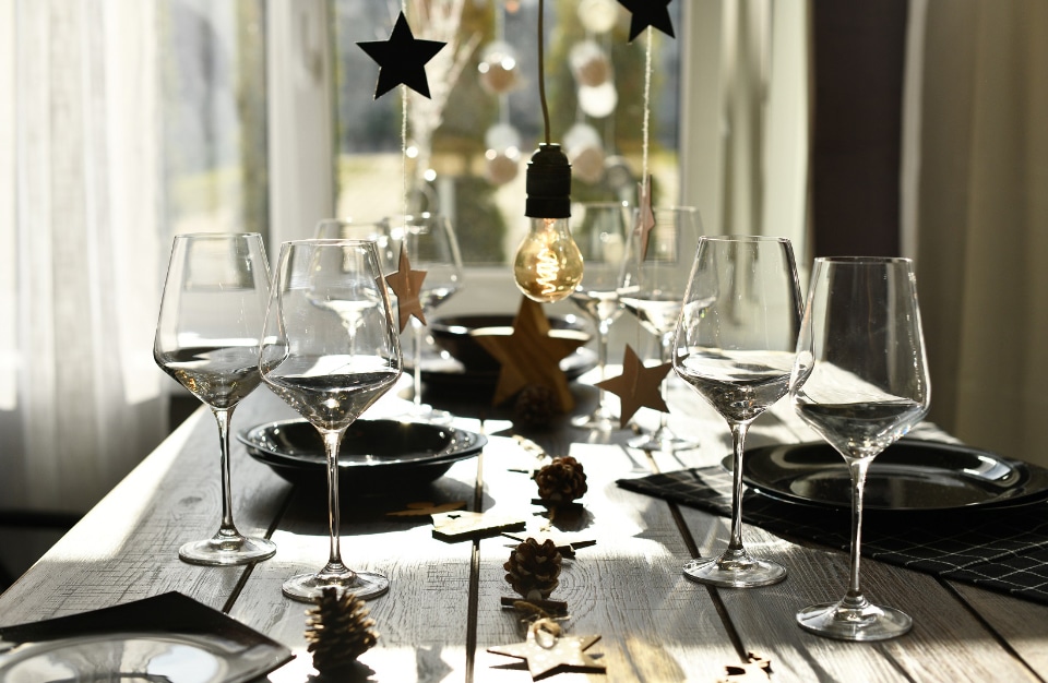 długi stół z czarną zastawą i szklanymi kieliszkami przy ozdobach świątecznych
