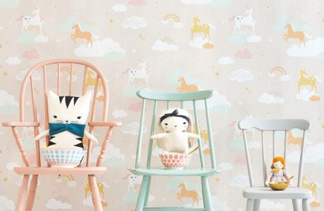 wyjątkowa tapeta do pokoju dziecięcego z jednorożcami chmurkami i tęczami na tle trzech krzeseł z przytulankami