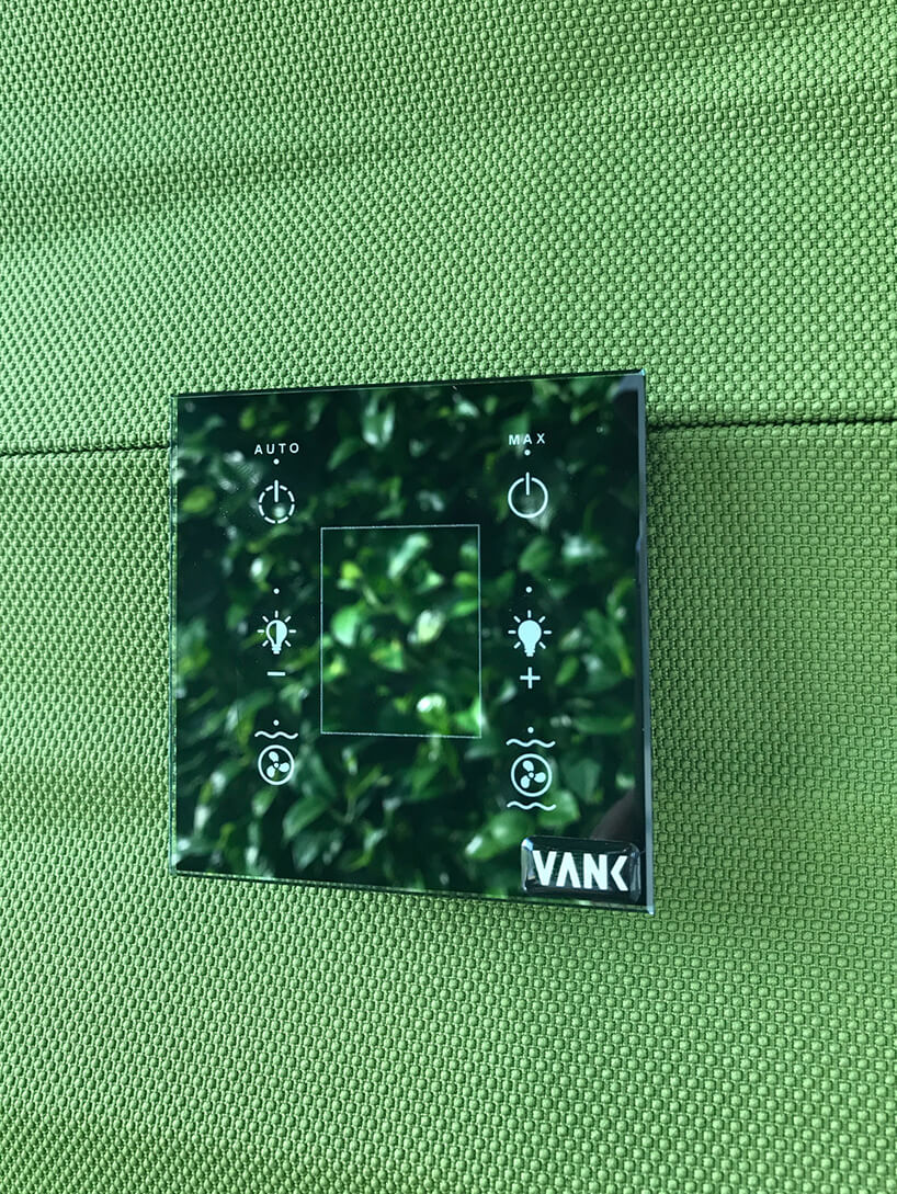szklany panel sterowania boxem akustycznym VANK_WALL JUNGLE na zielonej ścianie materiałowej