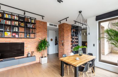 wnętrze w stylu hygge salon z ceglanymi ścianami małym stołem z drewnianym blatem i czterema czarnymi krzesłami