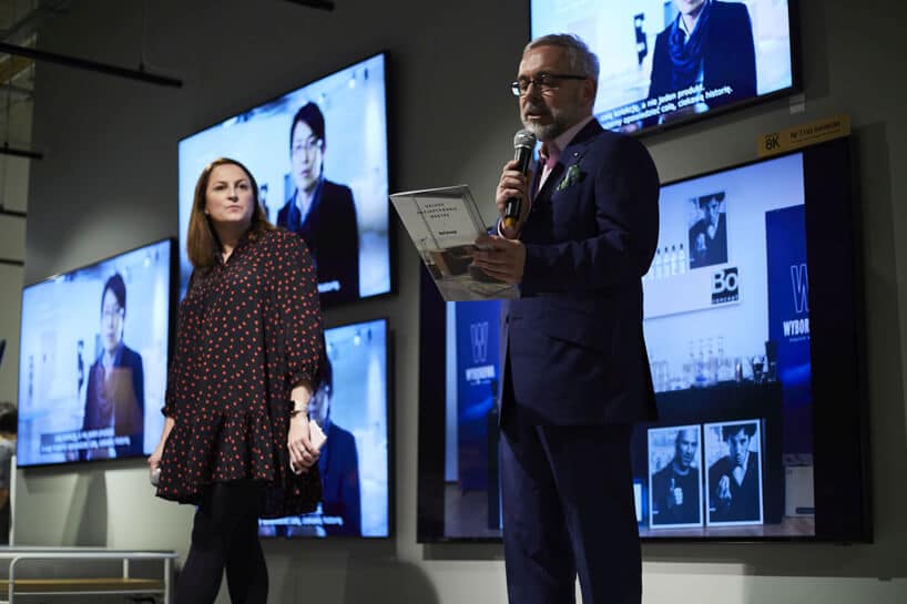 prowadzący 20-lecie BoConcept w Polsce na tle kilku ekranów