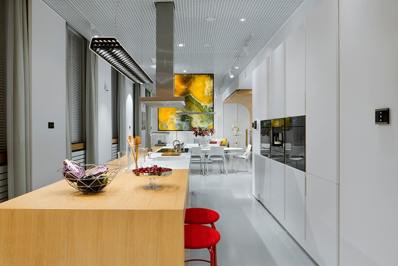 nowoczesne wnętrze Smart od ABB długa biała kuchnia z połączoną wyspa i stołem z dwoma stołkami