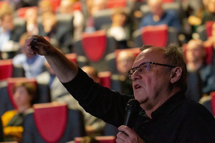 mężczyzna z mikrofonem na tle innych słuchaczy