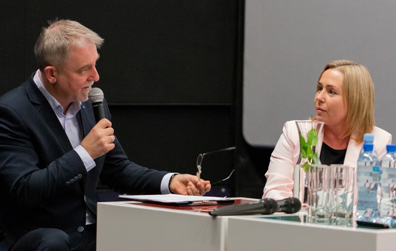 mężczyzna z mikrofonem podczas udzielania odpowiedzi obok kobiety w białej marynarce